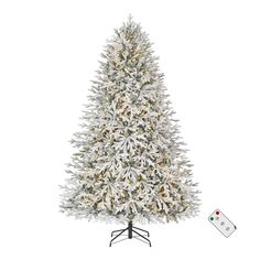 a white christmas tree with snow on it and a remote control in the foreground