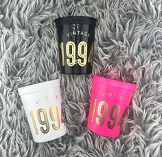 three different colored cups sitting on top of a carpet next to each other and one has the year 1994 written on it