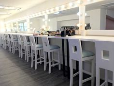 there are many bar stools at the counter with lights on each side and one chair in front