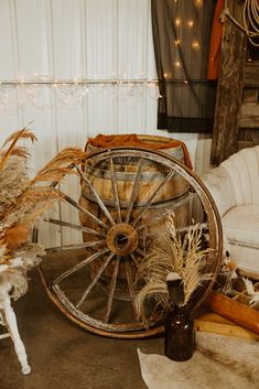 an old wagon wheel is surrounded by dried plants and other items in front of a white couch