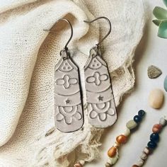 two silver earrings sitting on top of a white blanket