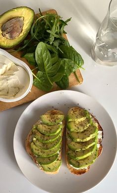 an avocado sandwich is on a white plate next to some other food items