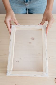 a person is holding a wooden frame with holes in the middle and their hands are on top of it