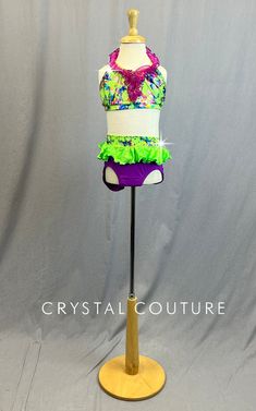 Lime Green and multi colored halter top includes a purple mesh ruffle that goes around neck and in a "V" down the center of bra. Same Lime Green fabric is the waistband of the Purple trunks, that also include a Lime Green shiny lycra ruffle. This costume has a little extra sparkle with size 20ss Peridot rhinestones sprinkled on Multi colored fabric. *Accessories include Purple fingerless gloves with Green ruffle, Green ankle bands and Purple headband with Green bow. **Costume in image is a YS, P Trio Costumes, Sequin Jewelry, Costumes Couture, Purple Headbands, Sequin Appliques, Rhinestone Appliques, Green Bows, Tutu Costumes, Tool Gifts