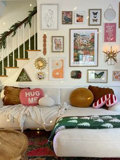 a living room filled with lots of furniture and pictures on the wall above it's stairs