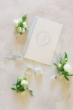 the wedding stationery is laid out on the floor with white flowers and greenery