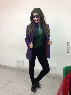 a woman dressed up as the joker in a room with white walls and tile flooring