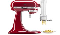 a red kitchen aid mixer next to a plate of pasta and a small bowl of food