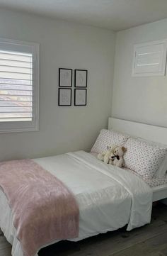 a small bedroom with a bed, window and pictures on the wall above it's headboard