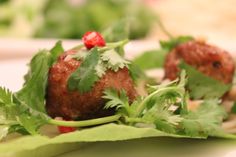 some meatballs are sitting on top of green leafy greens and garnishes