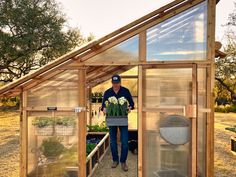 a man standing inside of a greenhouse with flowers in the potted area next to it