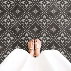 a woman's feet in white shoes standing on a black and white patterned floor