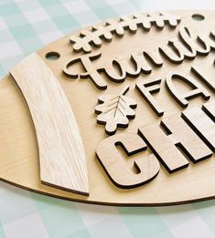 a wooden sign that says happy fall and chill with leaves on it, sitting on top of a checkered tablecloth