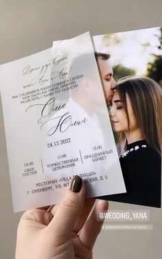 a person holding up a wedding card with an image of a man and woman on it