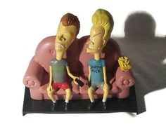 two cartoon figures sitting on top of a pink couch