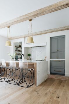 a kitchen with an island and marble counter tops in front of a gray cabinetry