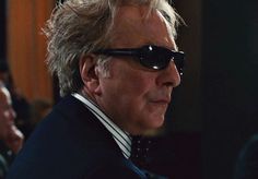 a man wearing sunglasses and a suit looks off into the distance