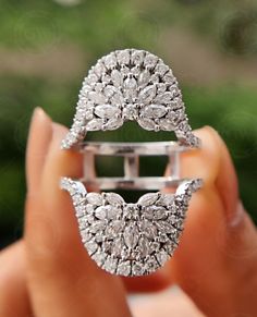 a woman's hand holding an open ring with diamonds on the outside and inside