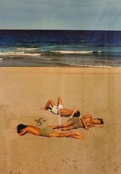 two people laying on the beach in front of the ocean