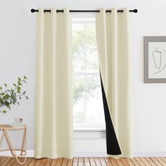 a white curtain hanging in front of a window next to a wooden floor with a potted plant