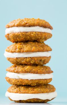 a stack of carrot cookies with icing and cream on top, against a blue background