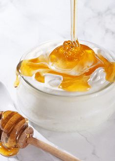 honey being drizzled into a glass jar filled with cream and honey syrup