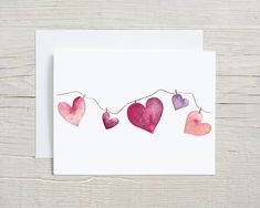 watercolor hearts are hanging on a string