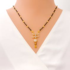 This 22k gold Mangal Sutra, weighing 9.9 grams, radiates festive charm with its stunning combination of black beads and cubic zirconia stones. The necklace measures 18" in length with a 1.5" drop, and adjustable 1" links offer a flexible fit. Finished in yellow gold, its hook lock ensures secure wear while adding to its elegance. Ideal for special occasions, this piece captures the perfect blend of tradition and sparkle, making it a dazzling addition to your jewelry collection. PRODUCT DETAILS Gold Purity(karat): 22k Item Weight(grams): 9.9 Item Finish: Yellow Gold Stone: Black Bead + Cubic Zirconia Necklace Length: 18" Drop Length: 1.5" Adjustable Links: 1" Links Lock Style: Hook Lock Elegant Black Temple Necklace For Festive Occasion, Festive Black Necklace With Gold Beads, Black 22k Gold Jewelry With Round Beads, Elegant Black Temple Necklace As Gift, Elegant Black Temple Necklace Gift, Festive Black Necklace In 22k Gold, Festive Gold Necklace With Black Beads, Traditional Yellow Gold Jewelry With Black Beads, Festive Gold Necklaces With Black Beads