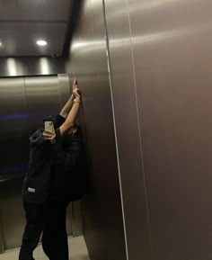 a man is standing in an elevator and reaching up to grab something off the wall