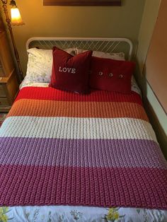 a bed with two pillows on top of it next to a night stand and lamp