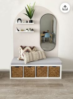 a white bench with baskets under it and a mirror above it on the wall behind it