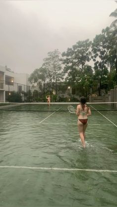 two people playing tennis in the water on a cloudy day with no shoes or clothes