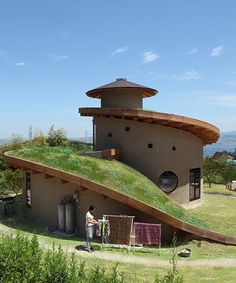 a person standing in front of a building with a green roof and grass on top