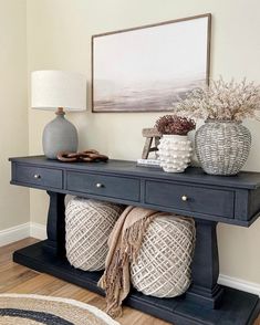 a table with two vases on top of it next to a rug and lamp