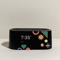 an alarm clock with different designs on the front and back side, sitting on a white surface