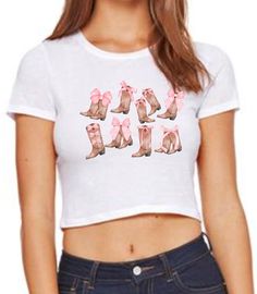 🎀 Cowgirl Boots with Pink Bows Baby Tee Coquette Aesthetic Graphic Tee  This baby tee is the perfect addition and  an absolute essential for this season's style!  ⭐️ STYLE OF TOP ⭐️ Baby Tee (XS/S) (M/L) Ladies' Poly-Cotton Crop T-Shirt Features 3.6 oz., 52% combed and ringspun cotton, 48% polyester 40 singles Slim fit Sideseamed Tear-away label ⭐️SIZING ⭐️ Please use the size guide to determine which size is best for you. These are WOMEN'S BABY TEES and fit true to size!  They have a bit of st Cute Fitted Pre-shrunk T-shirt, Cute Country Shirts, Crop Graphic Tee, Cute Country, Cropped Graphic Tees, Western Graphic Tees, Bow Shirts, Pink Bows, Cute N Country