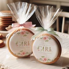 two cookies wrapped in cellophane and tied with bows on top of a table