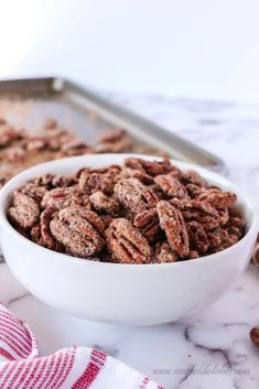 a white bowl filled with pecans sitting on top of a counter