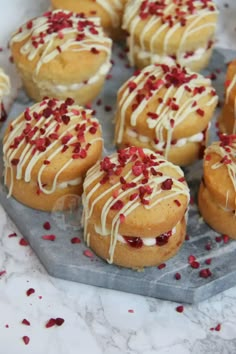 many small pastries with white icing and red sprinkles on a plate