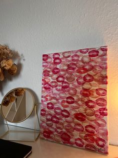 a painting is shown next to a mirror on a table with flowers and a cell phone