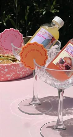 two wine glasses sitting on top of a table next to bottles of liquid and soap