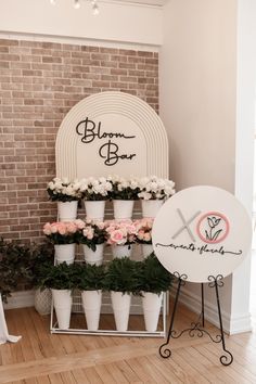 a flower shop display with white and pink flowers in potted planters next to a sign that says bloom & grow