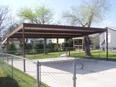 a covered patio in front of a house with a dog on the grass and trees behind it