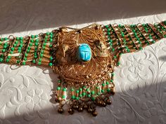 This is an amazing piece. The hand beaded detailing is amazing and unique! I believe the scarab may be turquoise or magnesite but I'm not entirely sure. The scarab beetle is surrounded on either side by 2 gold pharaohs. It has a hook clasp in back. It was very interesting (for those sensitive to energy)...I tried this choker on and felt a power surge through my throat and up through my crown. So, I know this is a powerful piece! This is a vintage item so please investigate the photos thoroughly David The Gnome, Egyptian Pharaoh, Egyptian Pharaohs, Scarab Beetle, A Hook, Photo Heart, Hook Clasp, Choker Necklaces, Beaded Choker