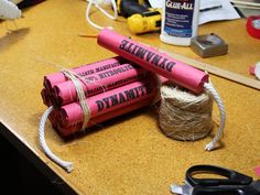 three pink dynamites sitting on top of a table next to twine and scissors