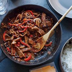 a skillet filled with meat and vegetables next to rice