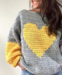 a woman wearing a crocheted sweater with a yellow heart on the chest and sleeves