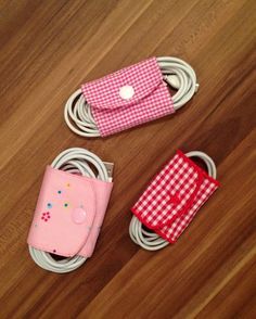 three cell phones are laying on the floor next to cords and charging devices, with one being plugged in