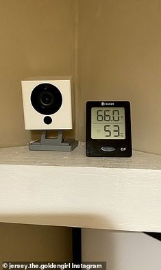 an alarm clock sitting on top of a white shelf next to a black and white clock