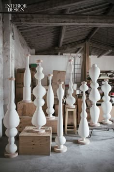 many white vases are stacked up in a room with boxes and other items on the floor